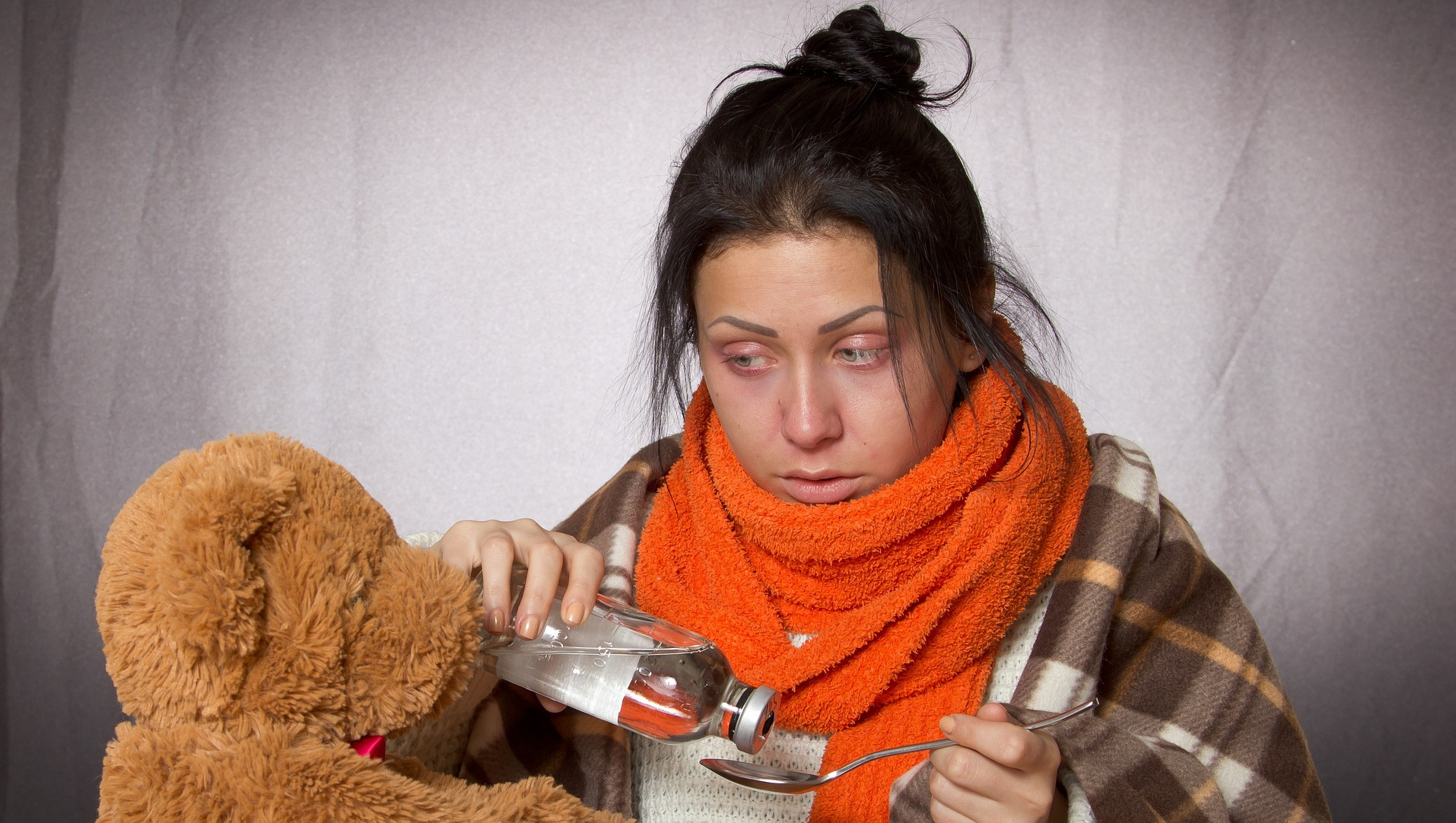 Young woman holding medicine with a teddy bear